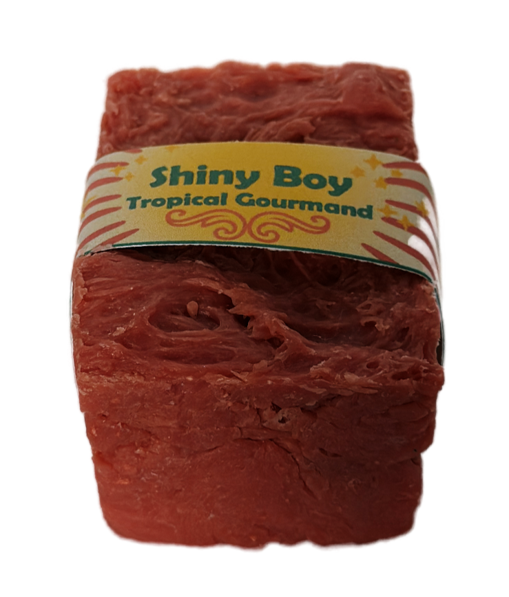 Coral-rose handmade soap bar with swirled rustic texture, wrapped in a vintage carnival-style yellow and cream band reading "Shiny Boy – Tropical Gourmand"