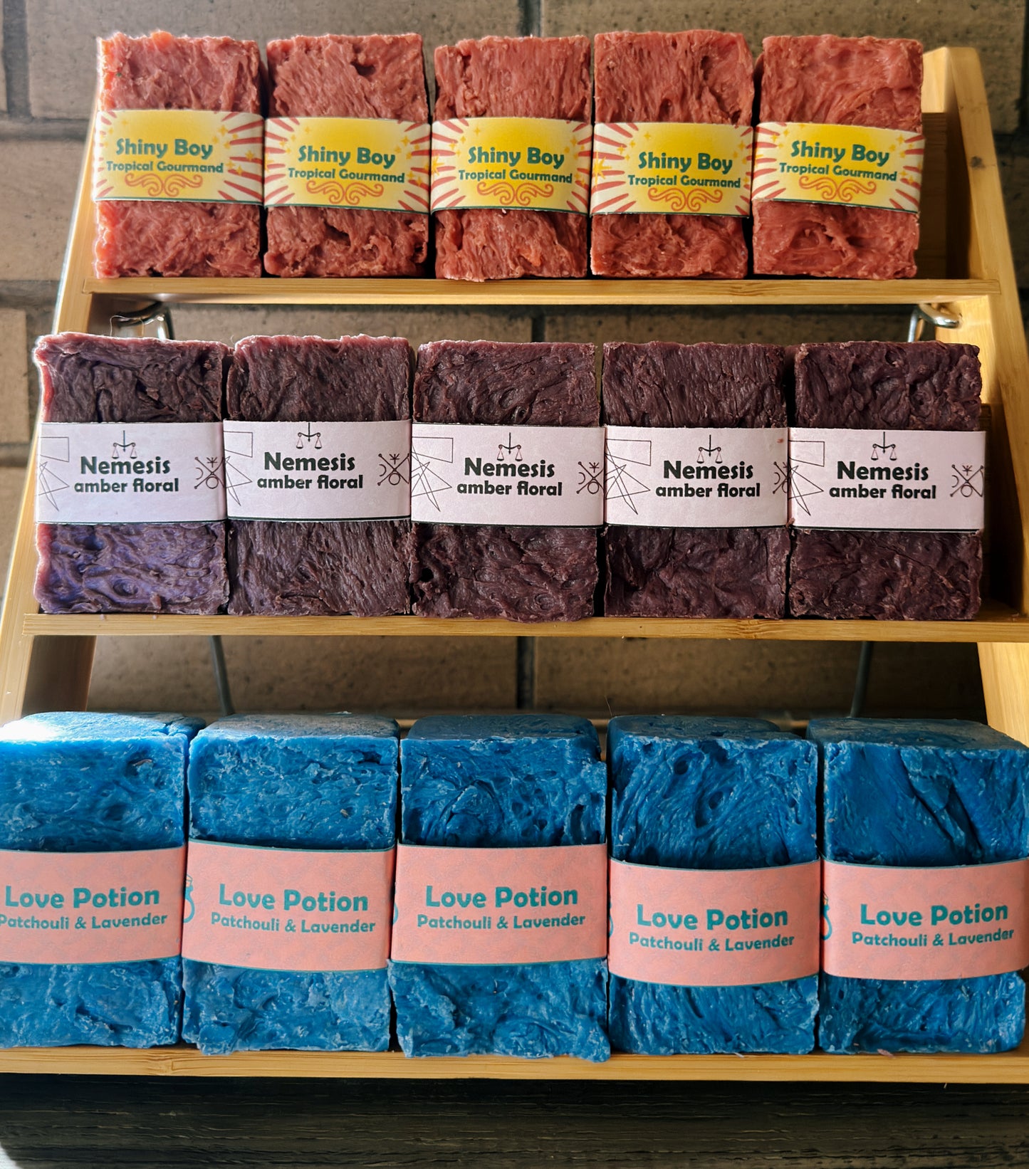 Display of various soaps with labels on a wooden rack.
