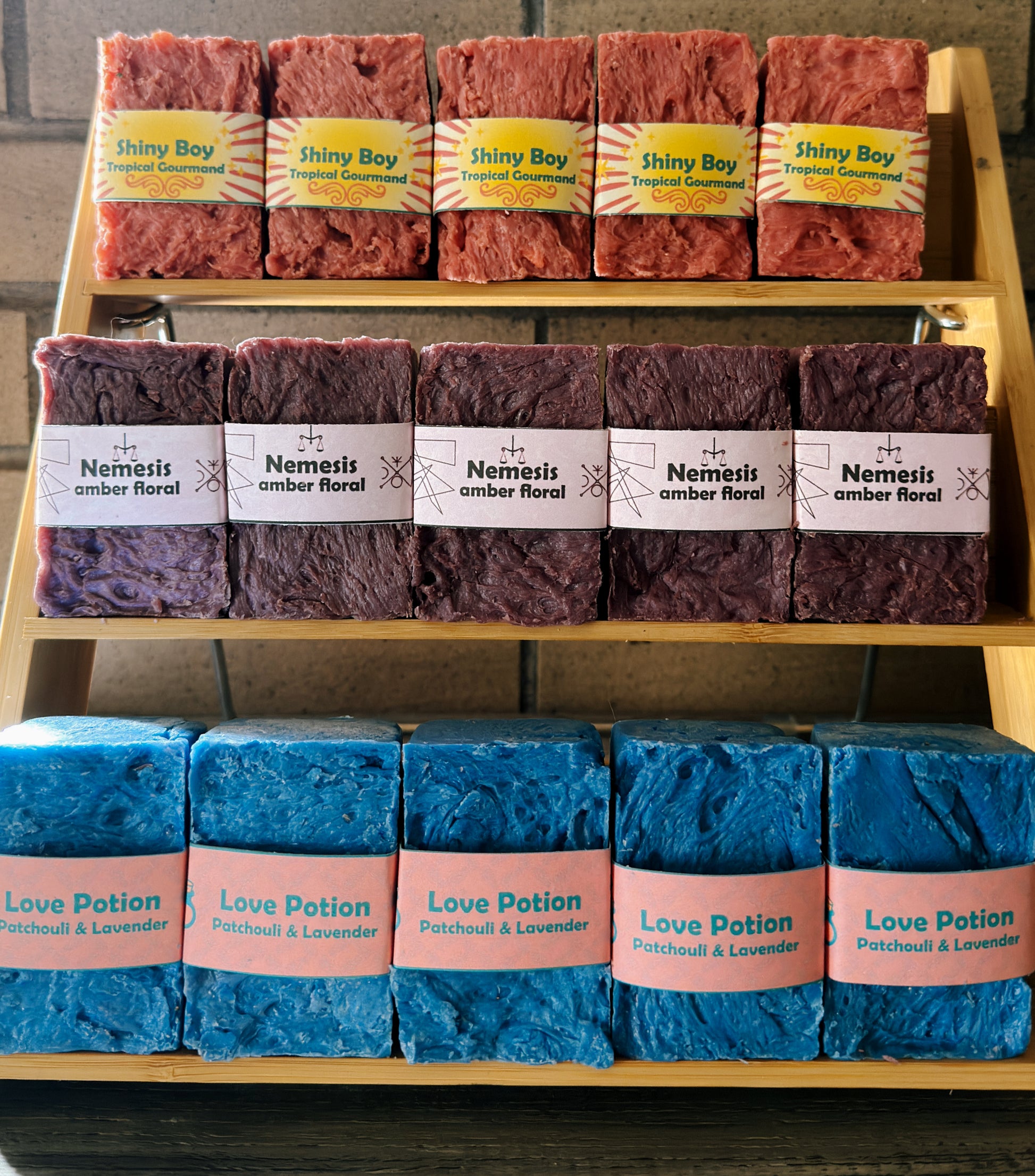Display of various soaps with labels on a wooden rack.