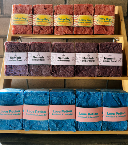 Display of various soaps with labels on a wooden rack.