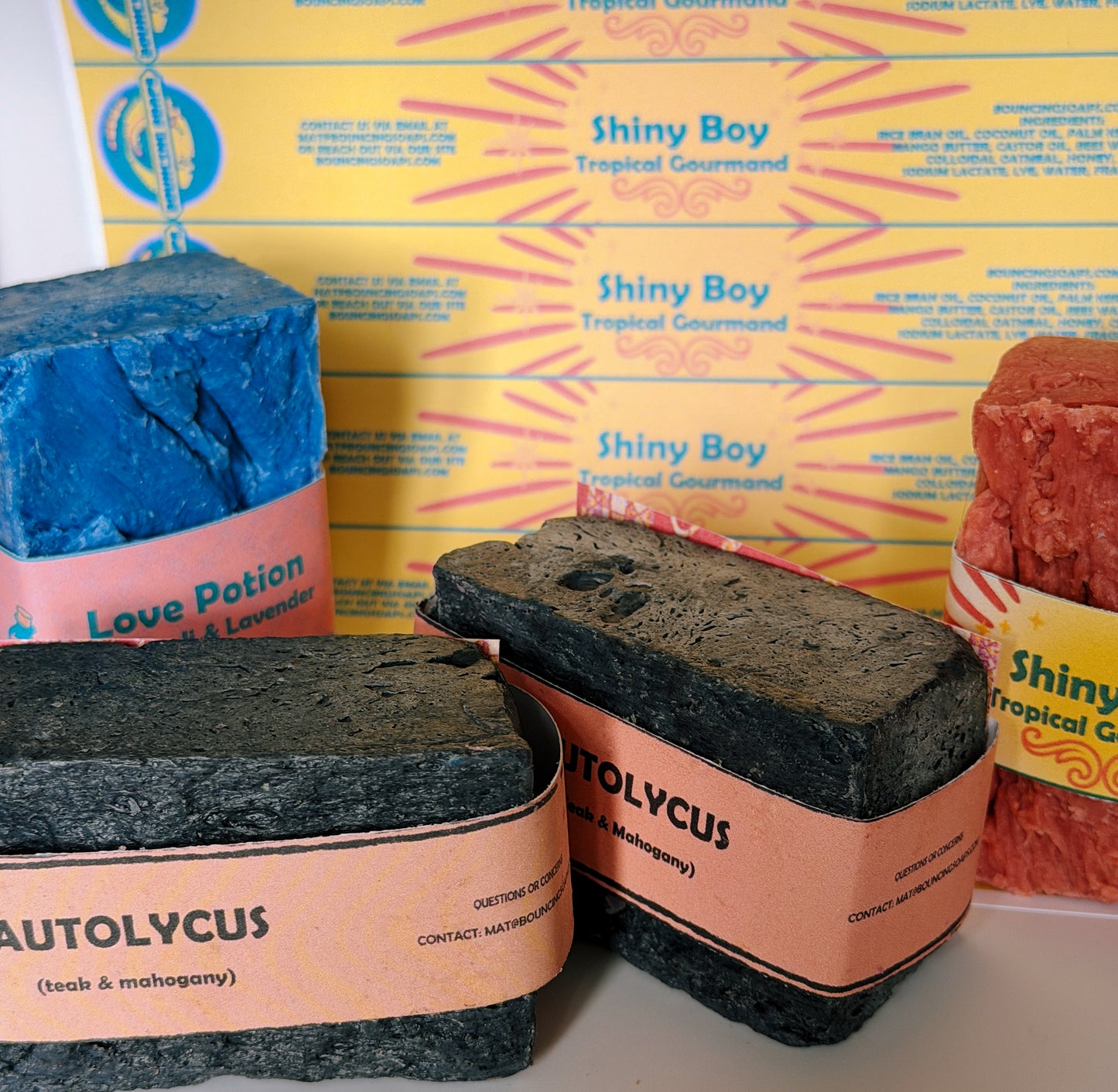 Three soap bars with different scents and packaging on a yellow box background.