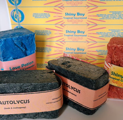 Three soap bars with different scents and packaging on a yellow box background.